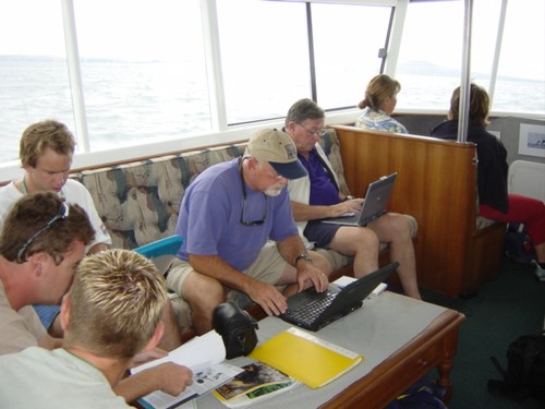 Hard at work America’s Cup tender - Auckland 2003. The hardworking chap in the blue shirt is Angus Phillips correspondent for The Washington Post. Bob Fisher is on his left shoulder © Larry Keating
